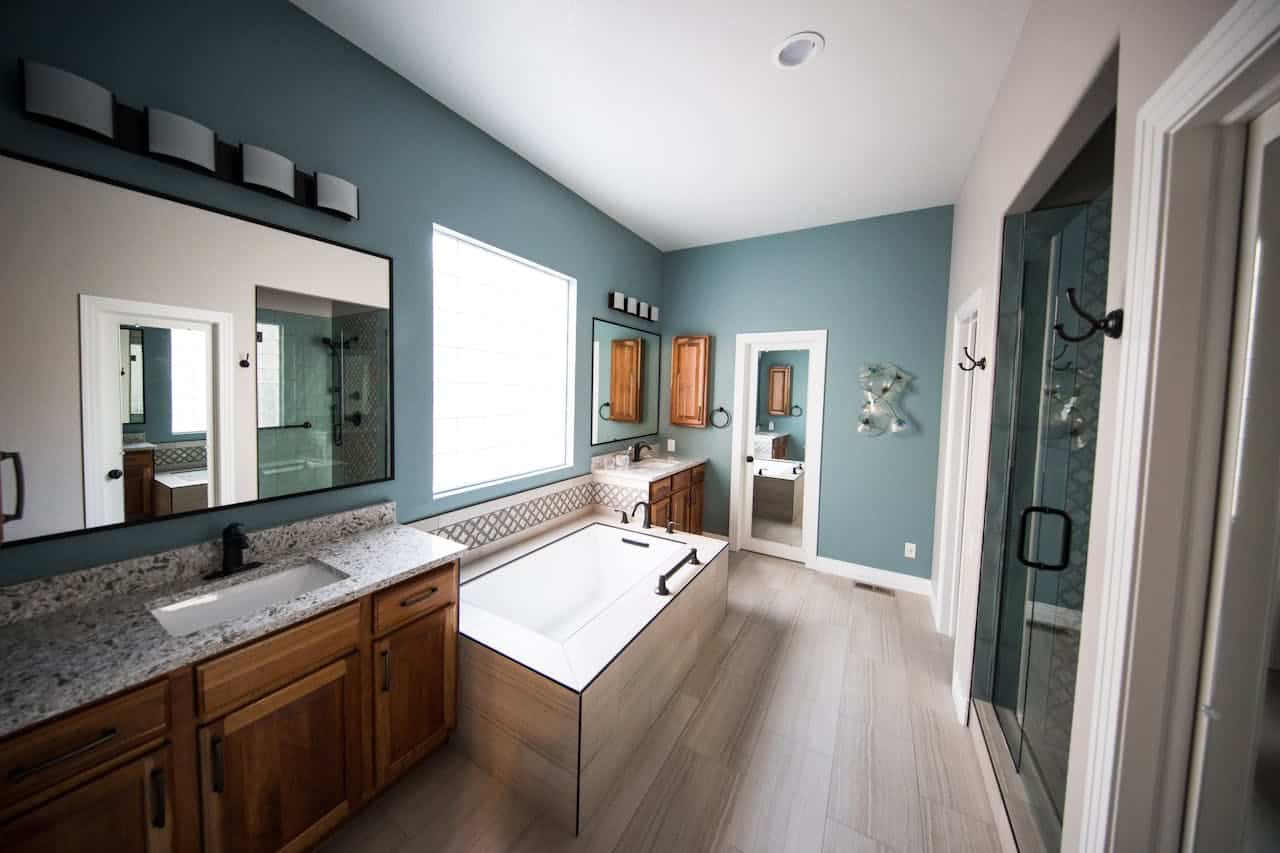 Spacious Bathroom Renovation with Soaking Tub Large bathroom with blue walls, soaking tub, double vanities, walk-in shower, and wood cabinetry.