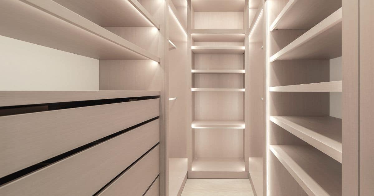 Custom cabinet shelves in a walk-in closet with LED lighting and built-in drawers for efficient storage
