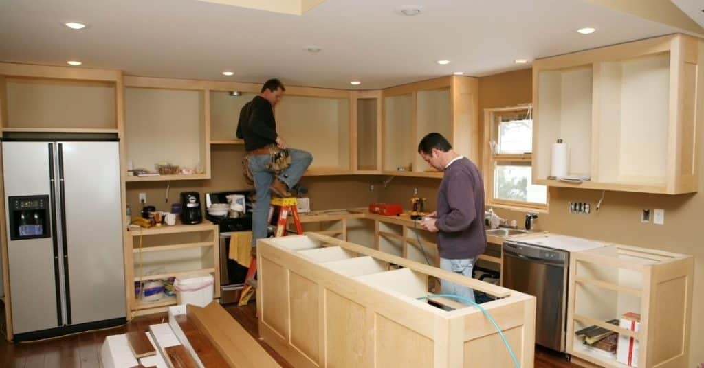 Worker drilling and building a kitchen island during a home renovation.