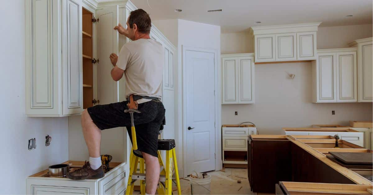 Final Cabinet Work in Kitchen Remodel Checklist Contractor finishing cabinet installation in a modern kitchen remodel.