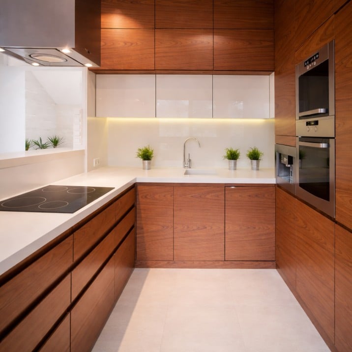 Modern kitchen with custom built wood cabinetry, white countertops, and built-in appliances.