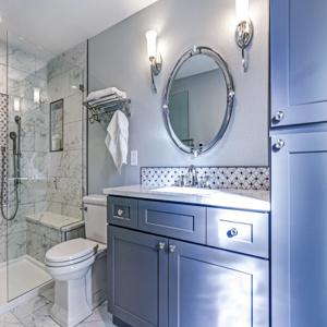 Modern bathroom remodel with glass shower, marble tiles, and gray vanity cabinet