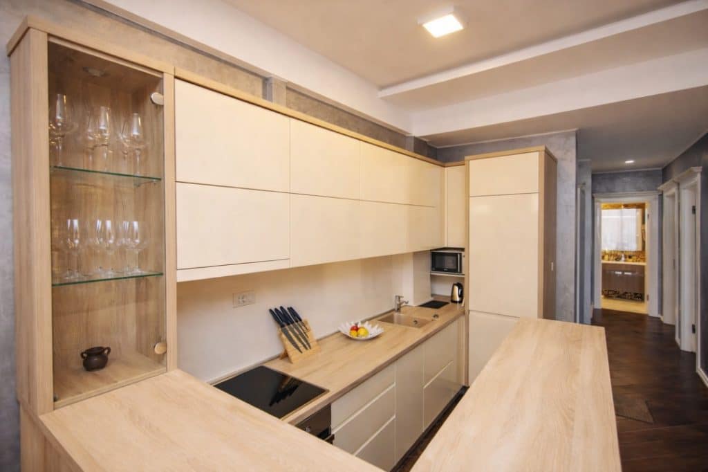 Modern built-in kitchen cabinetry with light wood countertop and glass cabinet.